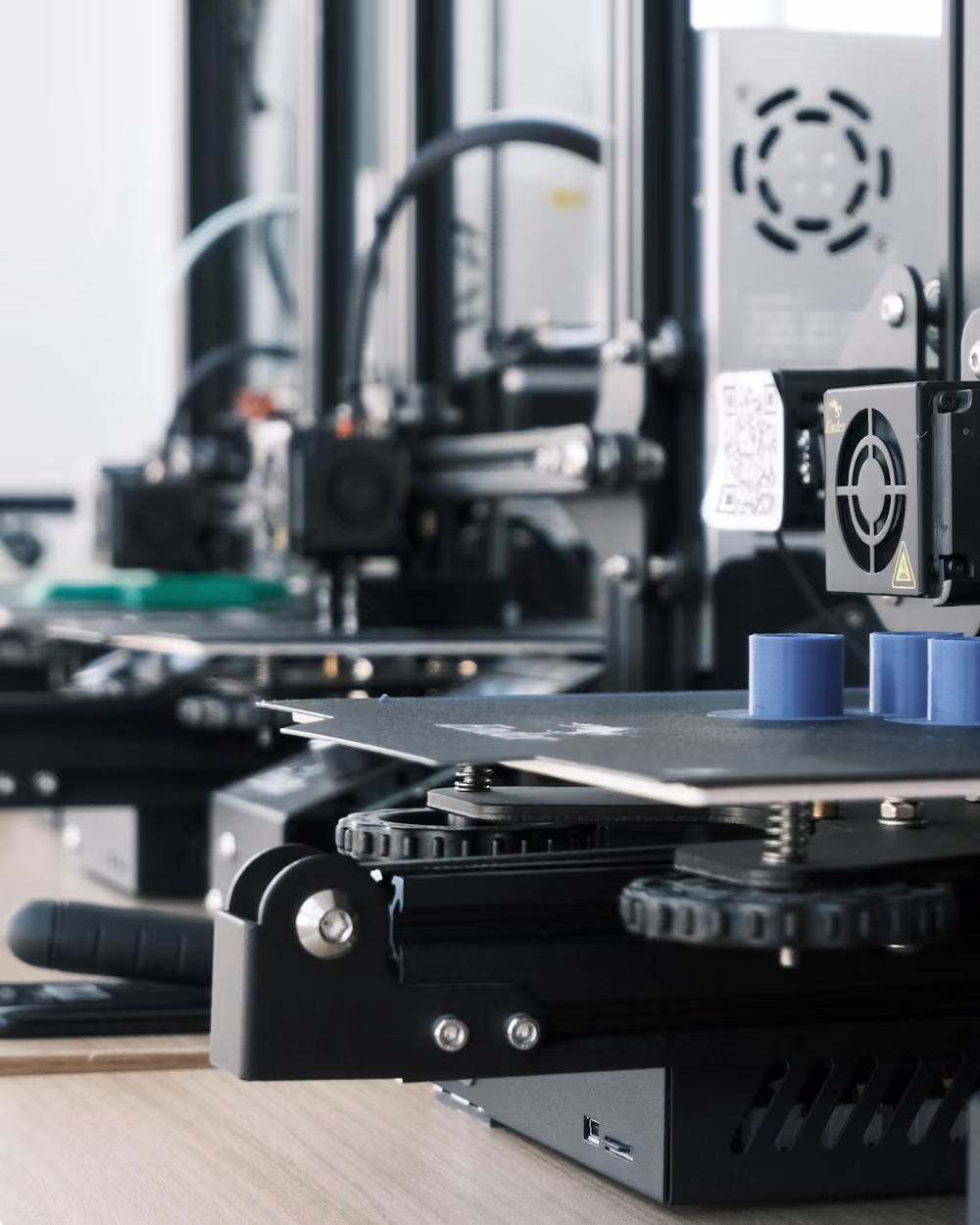 Varias impresoras 3D trabajando en paralelo sobre una mesa de taller