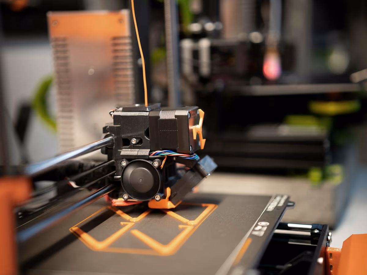 Impresora 3D depositando filamento sobre la cama caliente para formar una pieza